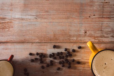 Kaliteli ahşap yüzeyde kahve çekirdekleri olan renkli kahve fincanları. Uzayı kopyala Seçici odak.