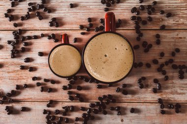 Eski ahşap yüzeyinde kahve çekirdekleri olan kırmızı kahve fincanları. Uzayı kopyala Seçici odak.