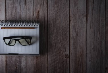 Notebook with pencil and glasses on wooden background. Top view. Copy space. Selective focus.