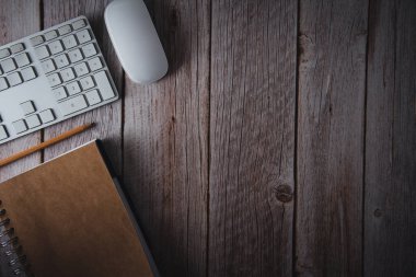 Çalışma alanı bilgisayar klavyesi, not defteri ve tahta arka planda kalemle. Üst Manzara. Uzayı kopyala Seçici odak.