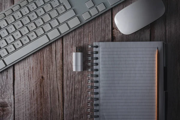Çalışma alanı bilgisayar klavyesi, fare, defter ve USB flash bellek ile ahşap arka planda. Üst Manzara. Uzayı kopyala Seçici odak.
