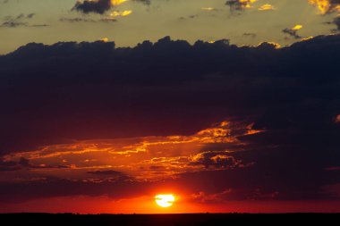 Colorful sunset on a cloudy day with big sun. Selective focus. Copy space. 