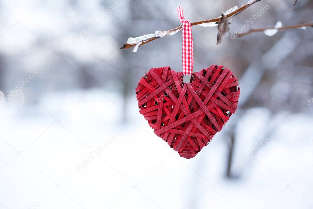 Valentines day background. Red heart on a branch against a background of snow, horizontal format for invitation or greeting card.