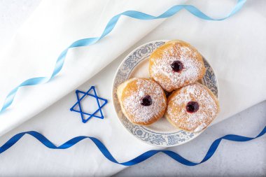 Mutlu Hanukkah 'lar, geleneksel çörekler mavi kurdeleli beyaz peçetede reçel sufganiyot ve yukarıdan David' in yıldız manzarası