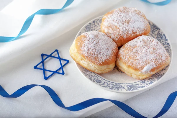 Mutlu Hanukkah 'lar, geleneksel çörekler mavi kurdeleli beyaz peçetede reçel sufganiyot ve yukarıdan David' in yıldız manzarası