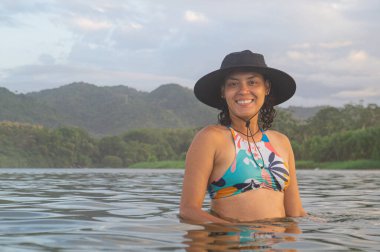 Sahilde şapka ve güneş gözlüğü takmış güzel bir genç kadının portresi.