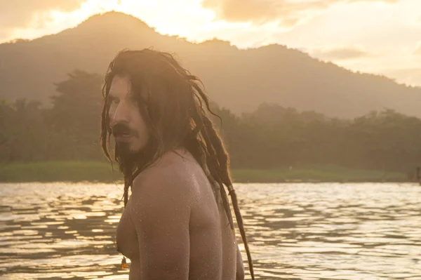 A portrait of a young man with long hair on the beach 