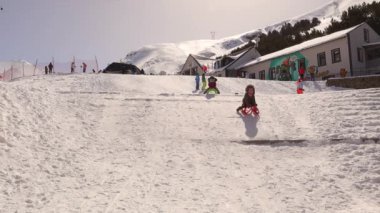 Erzurum, Türkiye. Çocuklar kar yamacında kızak sürüyorlardı ve çarpıştılar. Kamerayla, ama iyi ve heyecanlılar. Çocuklar birbirleriyle eğlenirler. çocuk yamaçta kayak yapıyor.