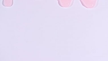 Pembe şeffaf kozmetik sıvısı. Beyaz yüzeyde molekül kabarcıkları akıyor. Makro Vuruş