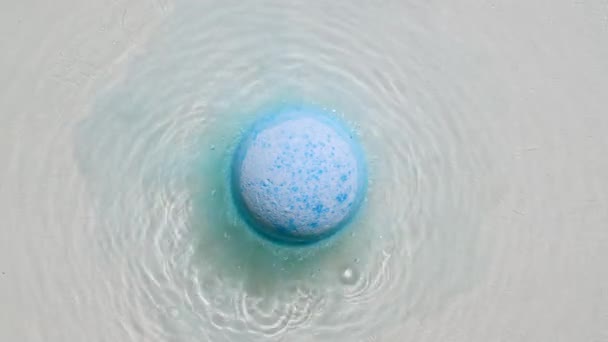 Μπλε μπάλα βόμβα μπάνιο διαλύεται σε νερό με λευκό αφρό φυσαλίδες. Αισθητικό προϊόν atural και φροντίδα του δέρματος. Καθαρό νερό με αντανακλάσεις, ηλιακό φως διάθλασης και σκιές. — Αρχείο Βίντεο