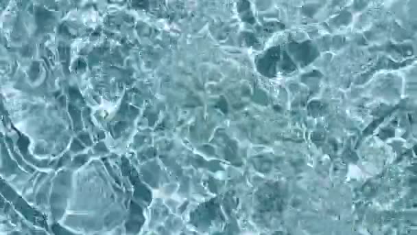 Текстура поверхности воды вид сверху. Вода брызгает синим цветом. Чистая голубая вода с отражениями солнечного света в замедленной съемке. Солнце и тени. Движение чистого бассейна рябь и волна. 4k — стоковое видео