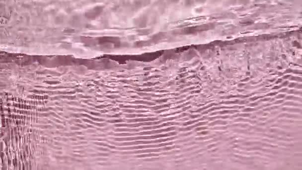 Eau rose pure avec reflets ensoleillés au ralenti. Soleil et ombres. Surface de l'eau texture vue de dessus. Motion propres ondulations de la piscine et vague. — Video