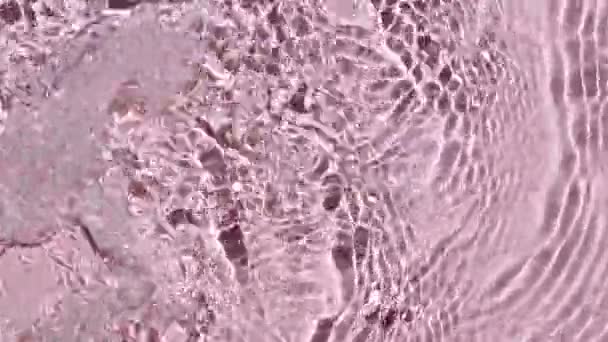 Water surface texture top view. Water splash pink colored. Pure blue water with reflections sunlight in slow motion. Sun and shadows. Motion clean swimming pool ripples and wave. 4k — Stock Video