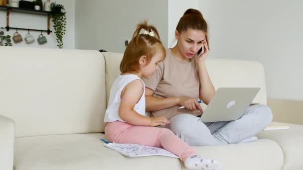 自宅で働く母親は、仕事のビデオ通話、電話を持ちながら、彼女の子供が気を散らし、注目を集めています。遠隔作業だ。電気ミュートの仕事 — ストック動画