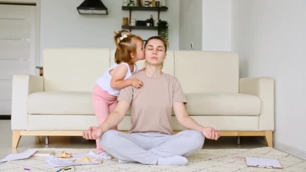 Mutter macht Yoga-Übungen zu Hause, um Stress abzubauen, während ihre kleine Tochter ablenkt und Aufmerksamkeit auf sich zieht. Zeitlupe — Stockvideo