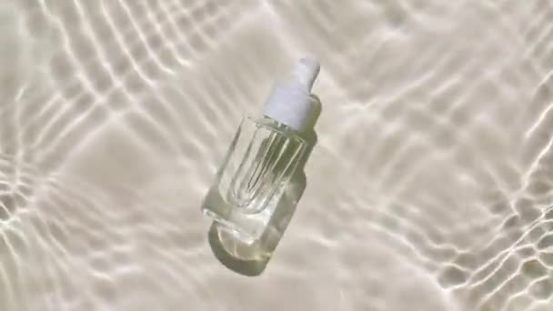 ガラス香水瓶、芳香族精油の化粧品。波の水のトップビューのスローモーション。反射、屈折した日光と影できれいな水。天然化粧品・スキンケア. — ストック動画