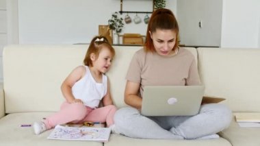 Annesi evde çalışıyor, çocuğu dikkatini dağıtıp dikkat çekerken iş videosu çekiyor. Uzaktan kumanda. Telekom işi