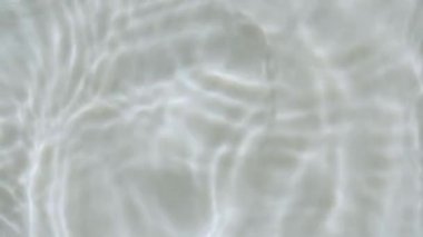 Su sıçraması. Su damlası dalgalanma yaratıyor. Güneş ve gölgeler. Güneş ışığını yavaş çekimde yansıtan saf su. Su yüzeyi üst görünümü. Temiz yüzme havuzu dalgalanmaları ve el sallamalar. 4k