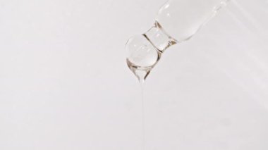 Beyaz zemin üzerinde yağ damlaları olan kozmetik pipeti