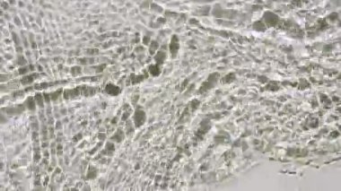 Su yüzeyi üst görünümü. Su, pastel renge boyanmış. Saf mavi su, güneş ışığını yavaş çekimde yansıtıyor. Hareket temiz yüzme havuzu dalgalanmaları ve el sallama. 4k