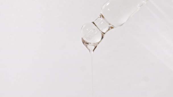 Pipeta cosmética con gotas de aceite de cerca sobre fondo blanco — Vídeos de Stock