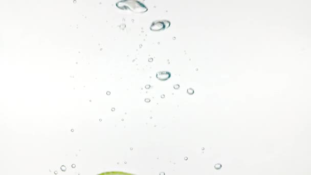 下降的柠檬片在水和空气中的缓慢运动,白色背景的气泡.宏观射门 — 图库视频影像