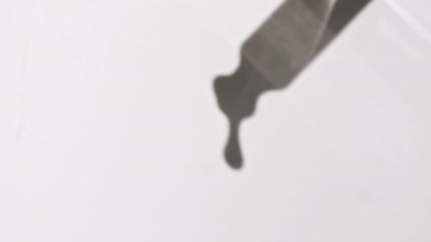Cosmetische pipet met druppels olie close-up op witte achtergrond — Stockvideo