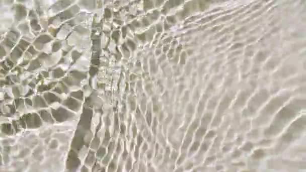 Reines beiges Wasser mit Reflexionen des Sonnenlichts in Zeitlupe. Oberflächenstruktur des Wassers von oben. Sonne und Schatten. Bewegung sauberes Schwimmbad Wellen und Wellen. — Stockvideo