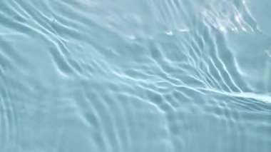 Su yüzeyi üst görünümü. Su mavi renklidir. Saf mavi su, güneş ışığını yavaş çekimde yansıtıyor. Güneş ve gölgeler. Hareket temiz yüzme havuzu dalgalanmaları ve el sallama. 4k
