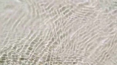 Su yüzeyi üst görünümü. Su, pastel renge boyanmış. Saf mavi su, güneş ışığını yavaş çekimde yansıtıyor. Hareket temiz yüzme havuzu dalgalanmaları ve el sallama. 4k