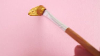 Pembe arka planda izole edilmiş altın fırça darbeleri. Altın boya lekesi dokusu. Altın renkli, dokulu, sanatsal çizim. Kozmetik kokuları.