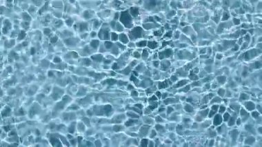 Su yüzeyi üst görünümü. Su dalgaları mavi renkli. Güneş ve gölgeler. Saf mavi su, güneş ışığını yavaş çekimde yansıtıyor. Hareket temiz yüzme havuzu dalgalanmaları ve el sallama. 4k