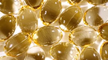 Sarı kapsüller tıbbi haplar, yakın çekim dönüşümlü. C vitamini, Omega 3 yağ kapsüllerinde. Haplar ve uyuşturucular. İlaç Endüstrisi. Tıp konsepti. Yavaş çekim