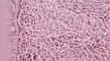 Saf pembe su, güneş ışığını yavaş çekimde yansıtıyor. Su yüzeyi üst görünümü. Güneş ve gölgeler. Hareket temiz yüzme havuzu dalgalanmaları ve dalga.