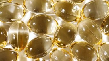 Sarı kapsüller tıbbi haplar, yakın çekim dönüşümlü. C vitamini, Omega 3 yağ kapsüllerinde. Haplar ve uyuşturucular. İlaç Endüstrisi. Tıp konsepti. Yavaş çekim