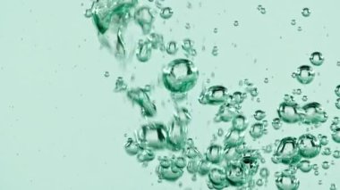 Açık mavi arka planda yükselen suyun içindeki makro hava kabarcıkları. Yavaş çekim.