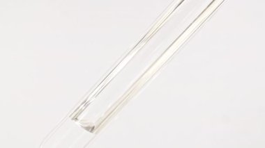 Pipette ve ilaç. Pipette 'in Macro karesi, su içinde ilaç ve beyaz arka planda hava kabarcıkları. Tıp konsepti, sağlık, tedavi. Yavaş çekim.