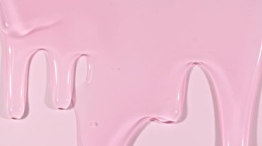 Pembe şeffaf kozmetik sıvısı. Beyaz yüzeyde molekül kabarcıkları akıyor. Makro Vuruş