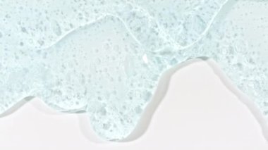 Şeffaf Mavi Kozmetik Jel Akıcı Kabarcıklar Beyaz bir yüzeye dökülüyor. Makro Vuruş