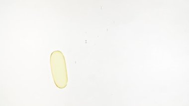 Kapsül hapları, Omega 3 altın yağ kapsülleri. Suya düşen hapların makro çekimi ve beyaz arka planda hava kabarcıkları. Tıp konsepti, sağlık, tedavi. Yavaş çekim.