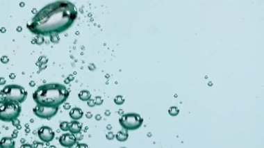 Açık mavi arka planda yükselen suyun içindeki makro hava kabarcıkları. Yavaş çekim.