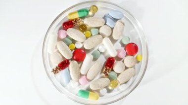 Renkli tıbbi haplar beyaz arka planda dönüşümlü olarak kullanılıyor. Haplar, vitaminler ve ilaçlar. İlaç Endüstrisi. Tıp konsepti. Makro atış. Yavaş çekim