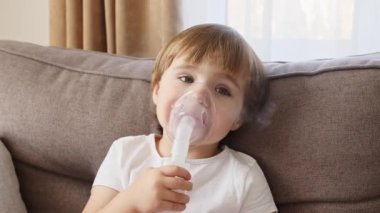 Maske takan küçük bir kız ciğerlerine duman ilacı soluyor. Çocuk evde astım spreyinden nefes alıyor.