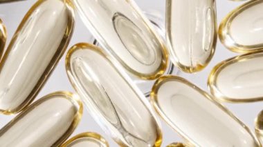 Sarı kapsüller tıbbi haplar, yakın çekim dönüşümlü. C vitamini, Omega 3 yağ kapsüllerinde. Haplar ve uyuşturucular. İlaç Endüstrisi. Tıp konsepti. Yavaş çekim
