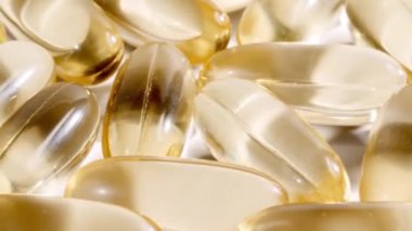 Sarı kapsüller tıbbi haplar, yakın çekim dönüşümlü. C vitamini, Omega 3 yağ kapsüllerinde. Haplar ve uyuşturucular. İlaç Endüstrisi. Tıp konsepti. Yavaş çekim