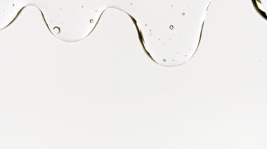 Beyaz bir yüzeye dökülen şeffaf kozmetik jel sıvısı. Makro Vuruş