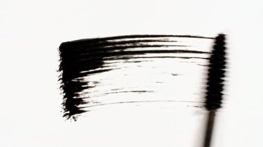 Makro çekim ve siyah rimelin yavaş çekimleri beyaz arka planda izole edilmiş. Profesyonel kozmetik reklamı. Beyaz arkaplandaki rimelin yakın plan görüntüsü.