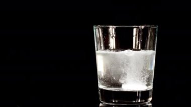 Siyah arka planda suyla birlikte bardağa düşen aspirin. Fışkırtıcı tablet aspirin. Tıp konsepti, sağlık, tedavi. Yavaş çekim