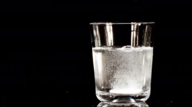 Siyah arka planda suyla birlikte bardağa düşen aspirin. Fışkırtıcı tablet aspirin. Tıp konsepti, sağlık, tedavi. Yavaş çekim