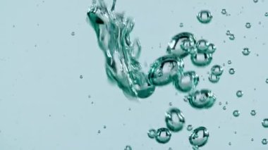 Açık mavi arka planda yükselen suyun içindeki makro hava kabarcıkları. Yavaş çekim.